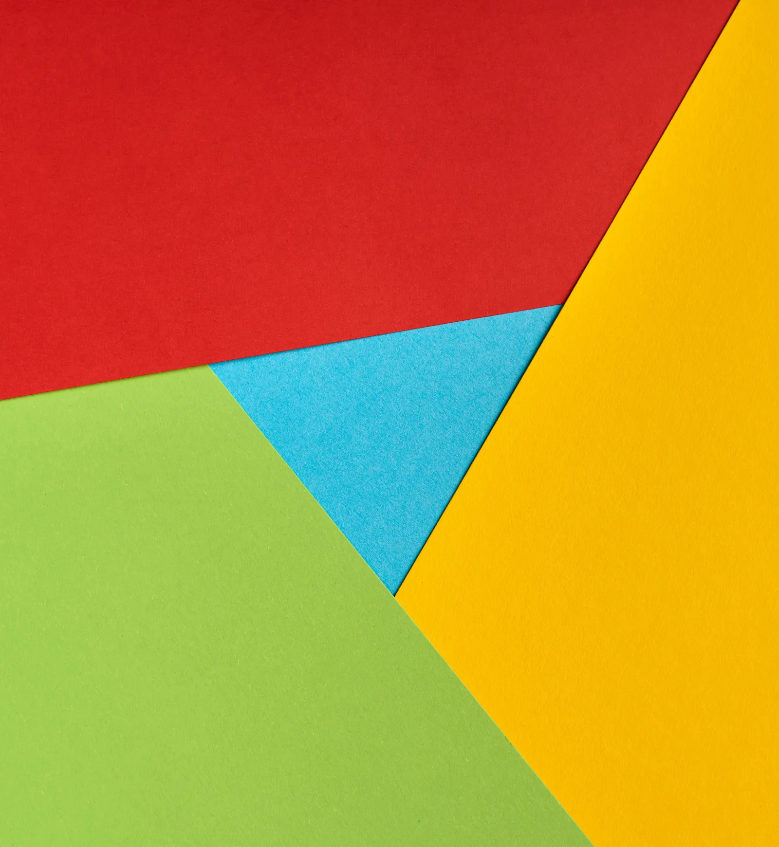 Farbige Papierflächen in Rot, Gelb, Grün und Blau, geometrisch übereinandergelegt